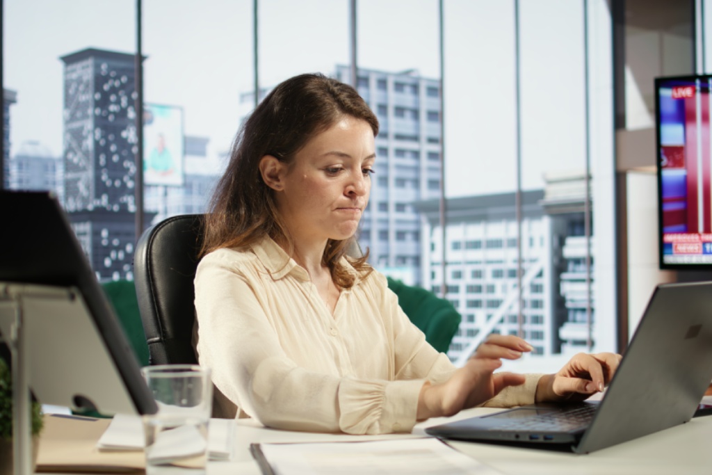 Office employee working on a computer while workplace monitoring systems are in use