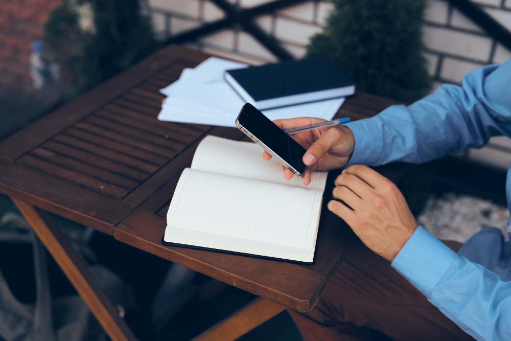 Cuaderno con el registro diario de horas trabajadas junto a un teléfono con mensajes del supervisor